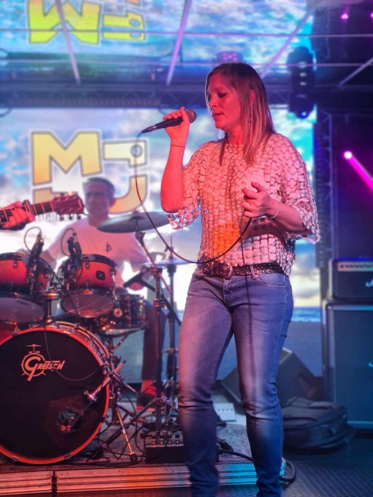 Mélanie au chant, devant l'enseigne MJ