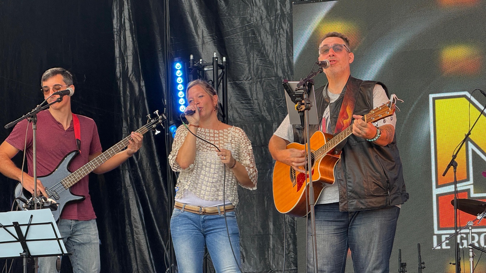 Le trio sur scène, devant le logo MJ